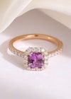 A unique, bright pink square sapphire ring with a diamond set band and hexagon shape diamond halo