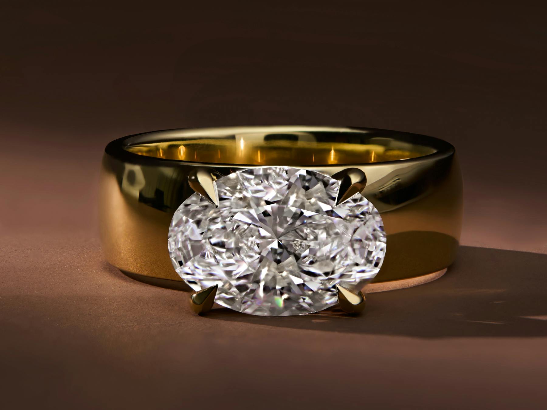 engagement ring with 2.36ct oval cut diamond set east-to-west on a chunky 18k yellow gold band.