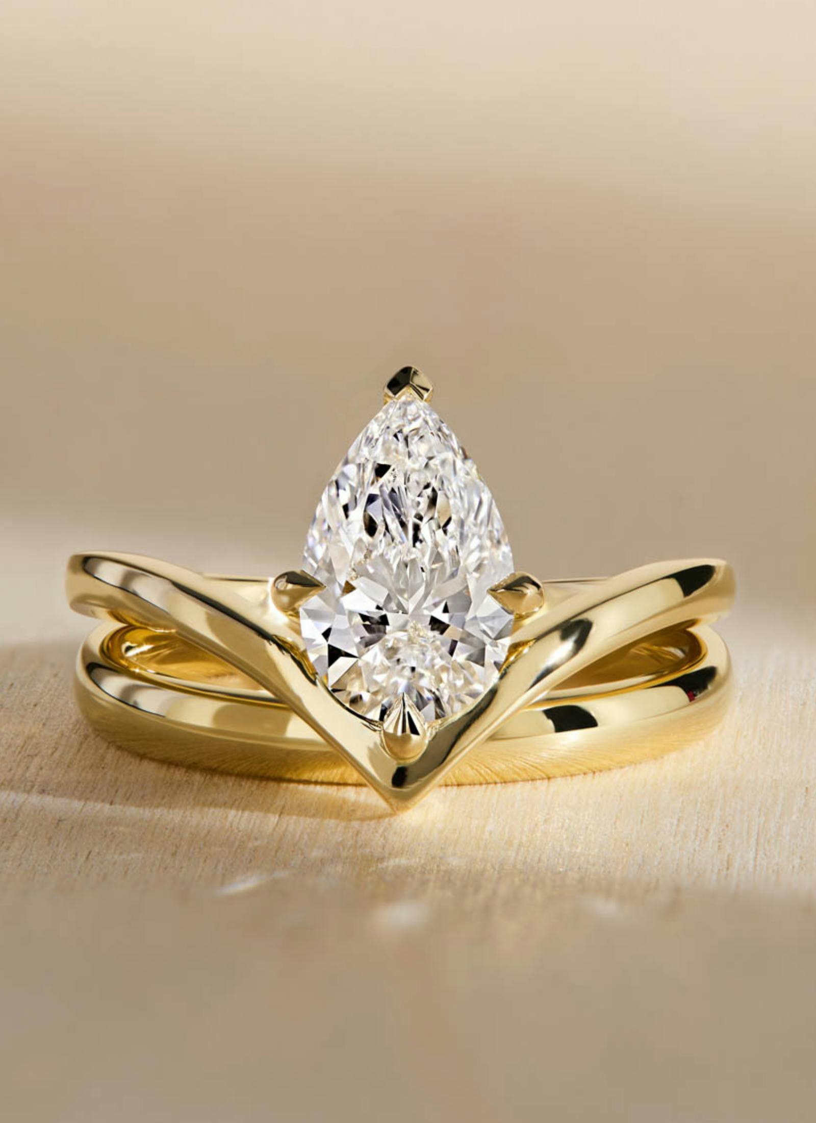 Bespoke engagement ring featuring a pear cut diamond in a yellow gold v-shaped band with yellow gold wedding ring, crafted for perfect fit and symmetry.