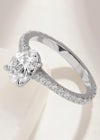 An oval diamond ring with scallop set diamond shoulders. This diamond band engagement ring is set in platinum with scalloped metalwork