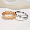 A thick, plain rose gold wedding ring next to a simple diamond wedding ring on a white background