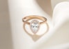Rose gold engagement ring with pear diamond centre stone and halo of small diamonds are the centre