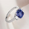 A rectangular trilogy sapphire engagement ring with diamond emerald cut sides
