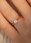 Close up of woman's hand wearing dainty round diamond, simple rose gold engagement rings