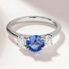 A round sapphire and diamond engagement ring set in a trilogy style