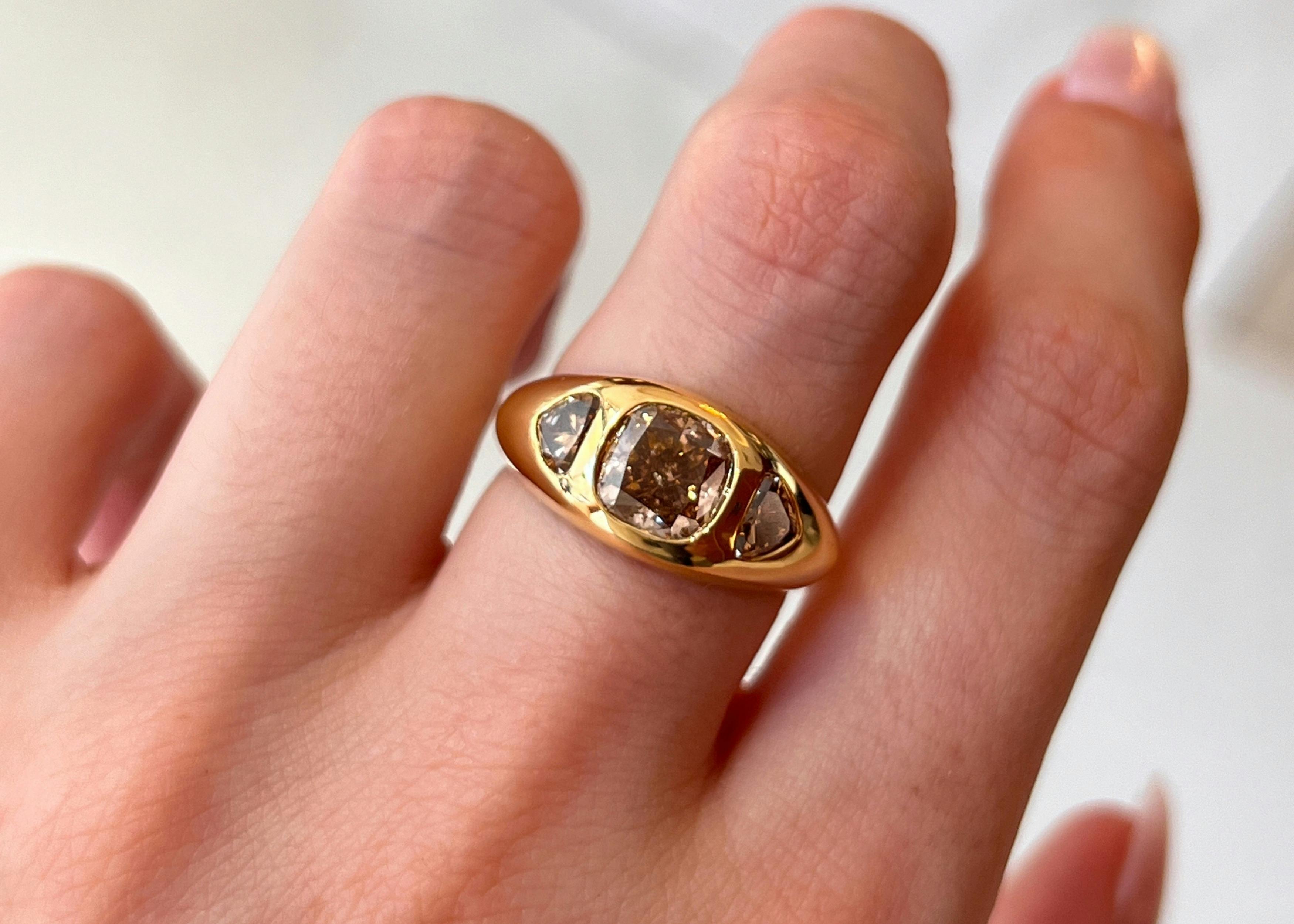 A close-up, birds-eye-view image of a woman's manicured hand, showcasing a yellow brown cushion cut 0.87ct yellow gold engagement ring.