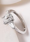 Emerald cut diamond trilogy engagement ring with side stones in a tapered baguette shape