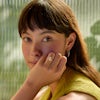 Woman wears oval diamond engagement ring in yellow gold.