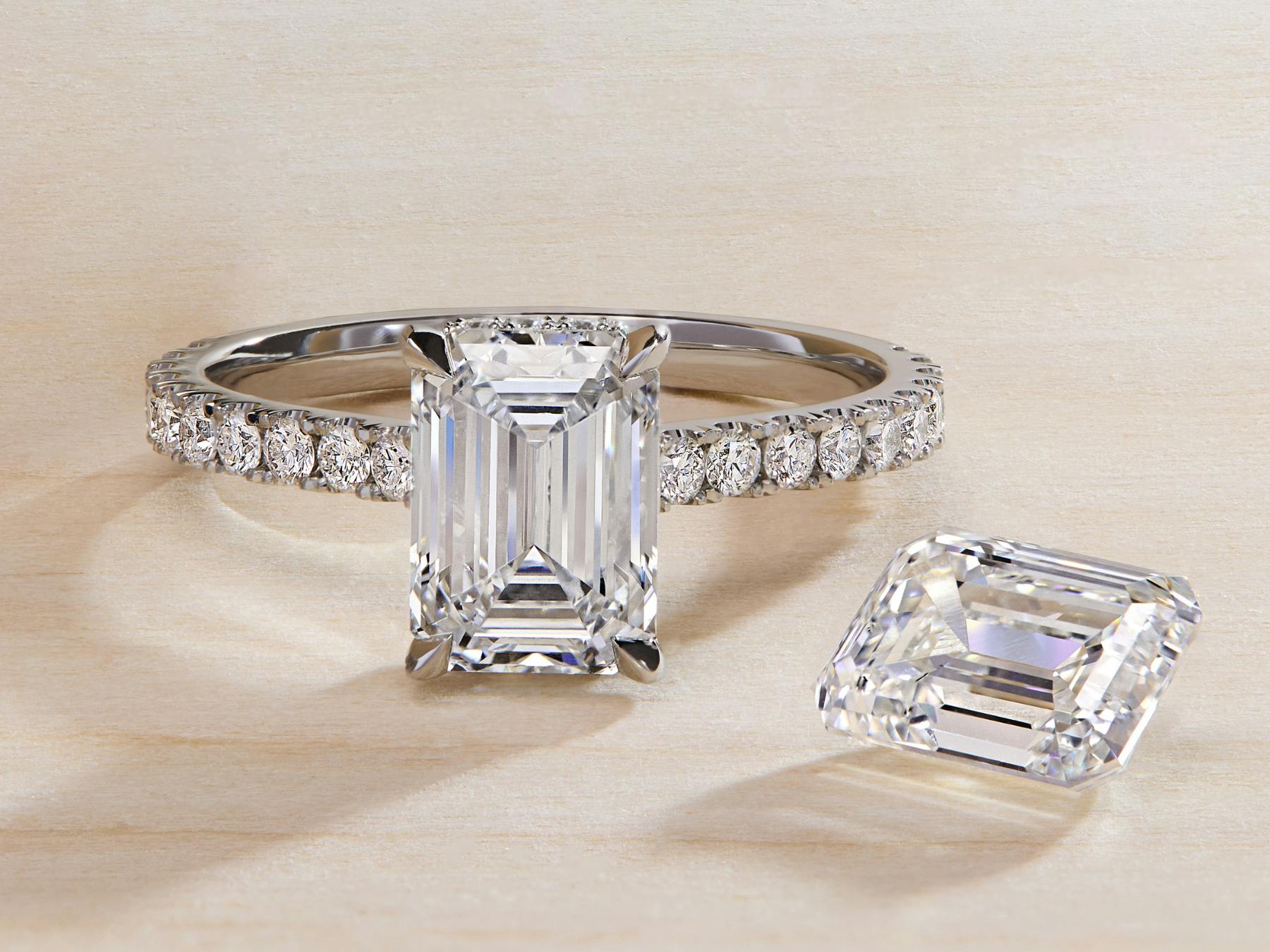 Diamond band engagement ring with emerald cut diamond and platinum setting.