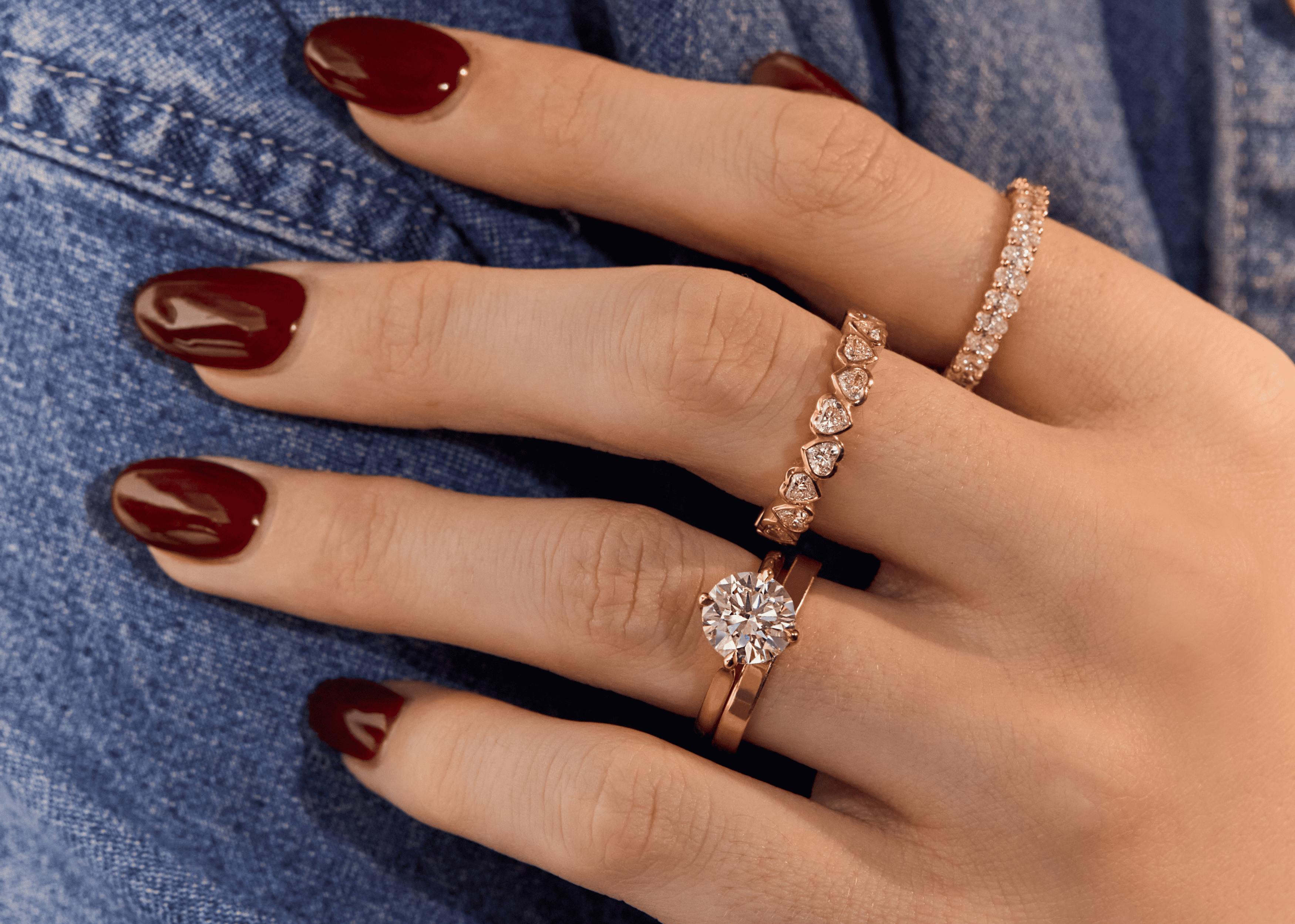 Gold engagement ring stack with round brilliant solitaire, wedding band and heart-shaped diamond ring and eternity ring.