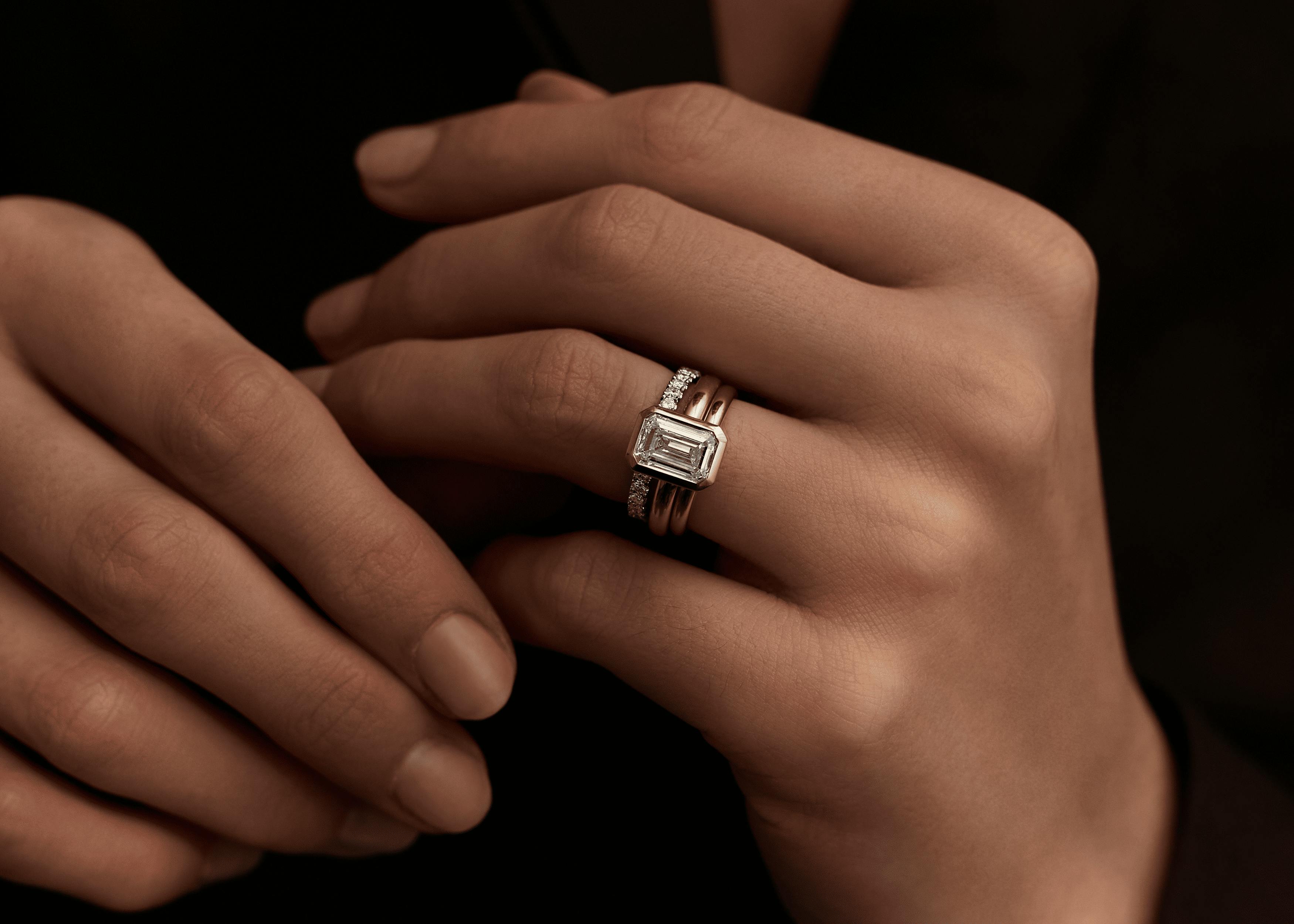 Emerald cut diamond engagement ring stack with rose gold band and diamond-set wedding ring.
