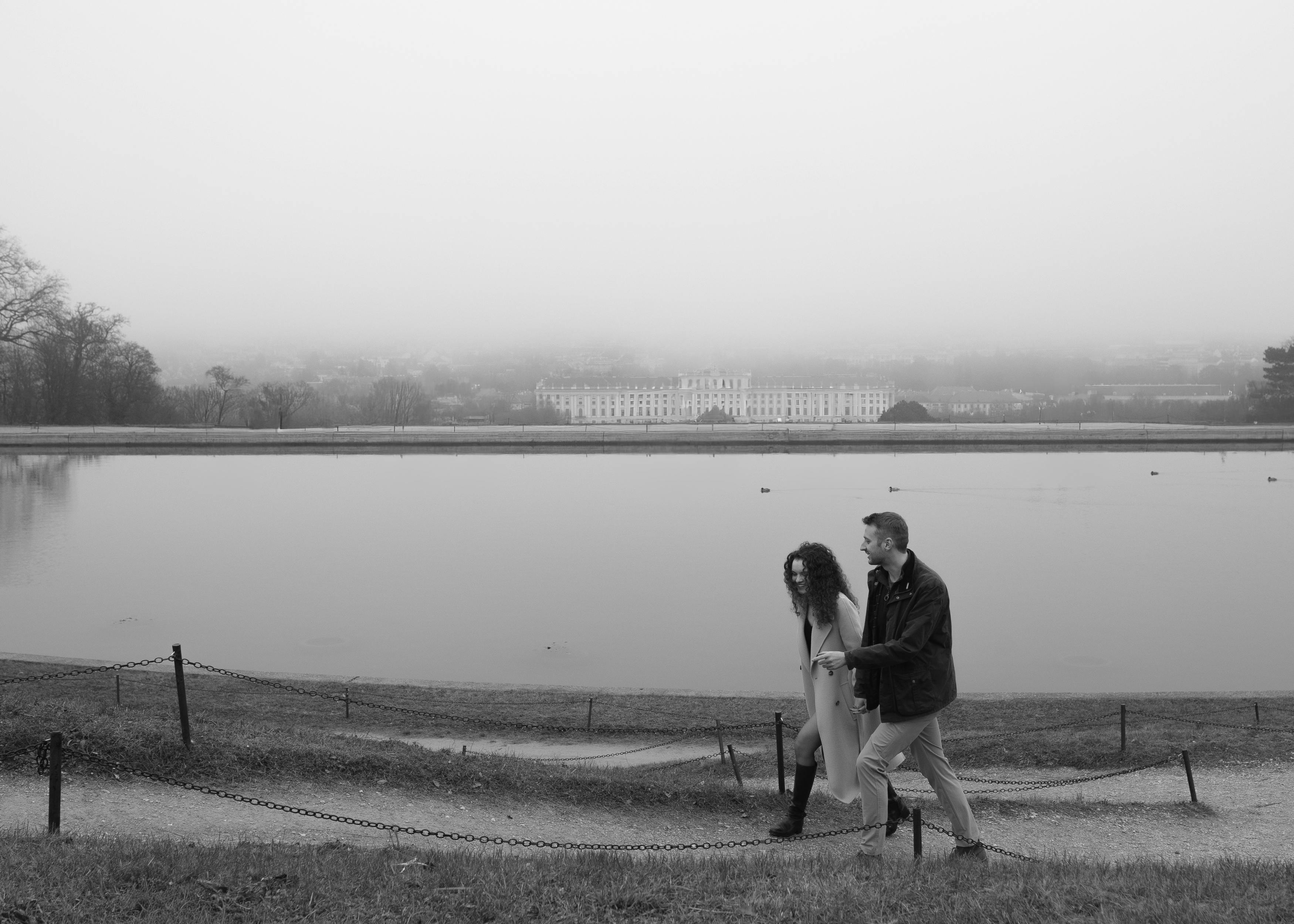 Black and white photograph of Samuel and Ella walking together along the Schönbrunn Palace gardens after their engagement.