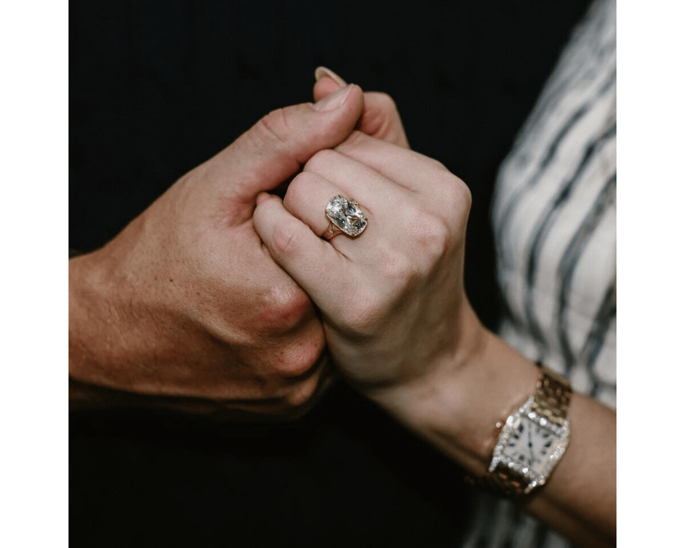 Taylor Swift holds Travis Kelce's hand, wearing old mine cut diamond engagement ring.