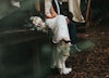 Bride and groom sit alone together on wooden platform.
