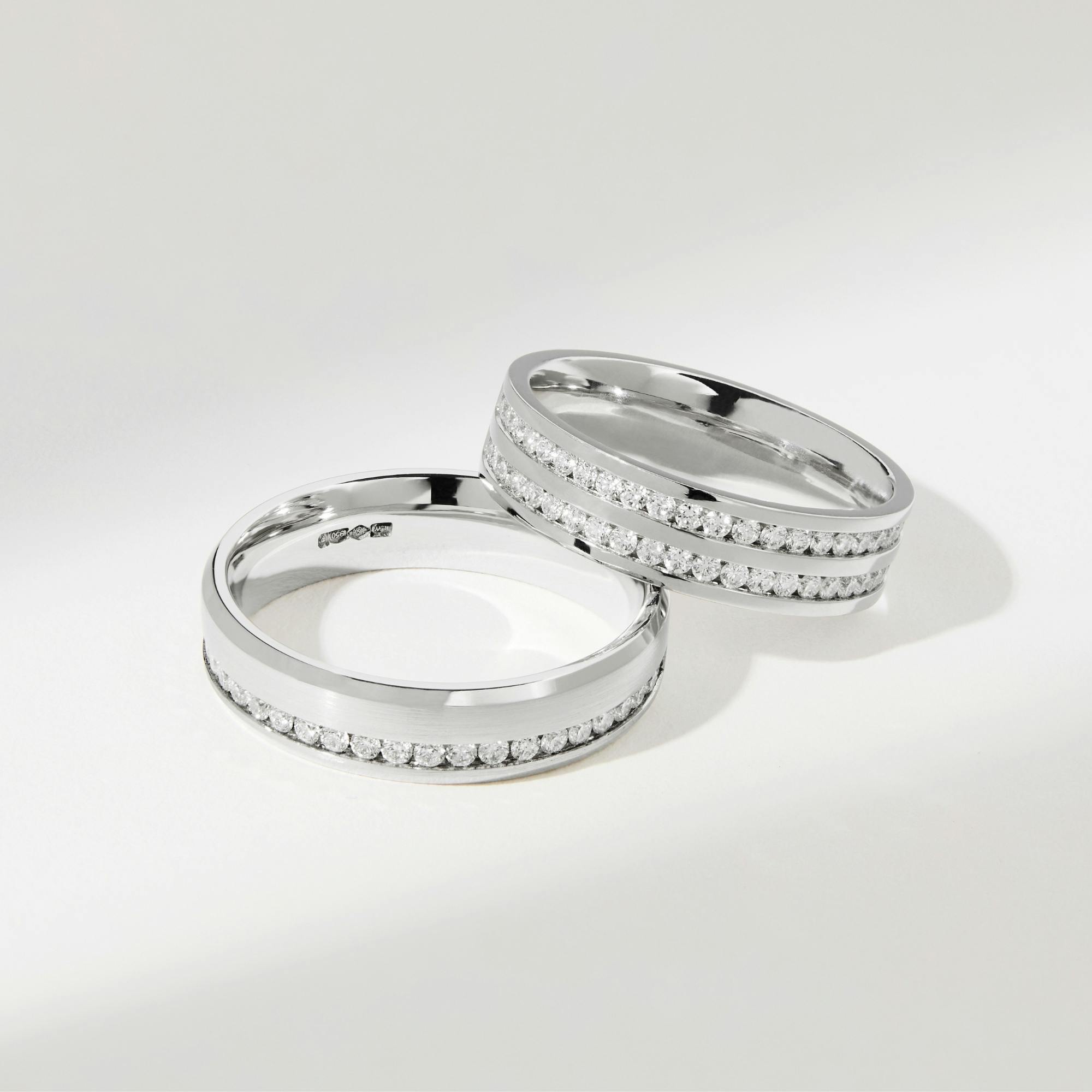 Close-up, front-view image of two platinum wedding bands with diamond channel settings.