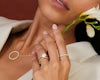 Woman wearing a collection of diamond jewellery, including a necklace, wedding ring, engagement ring and eternity ring.