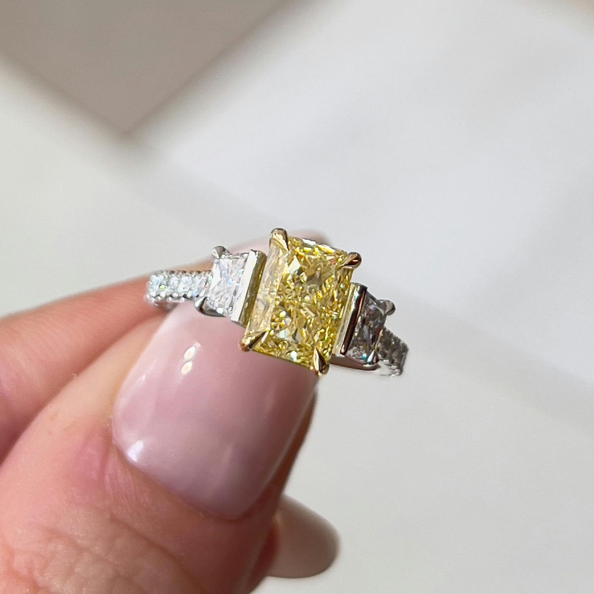 Close-up, aerial-view image of a radiant fancy yellow 0.40ct platinum and yellow gold trilogy engagement ring.