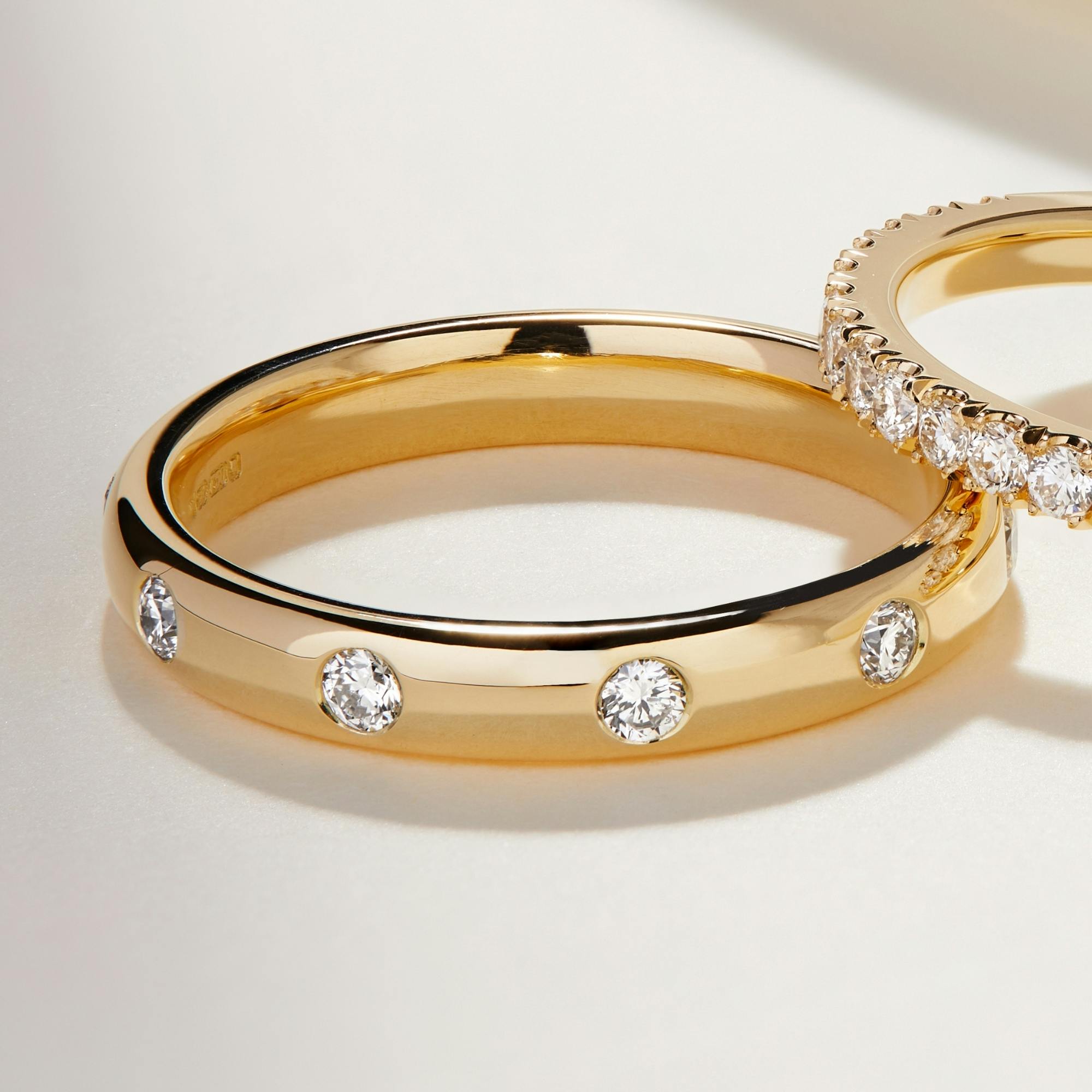A close-up image of a diamond wedding band in yellow gold with a flush diamond setting.