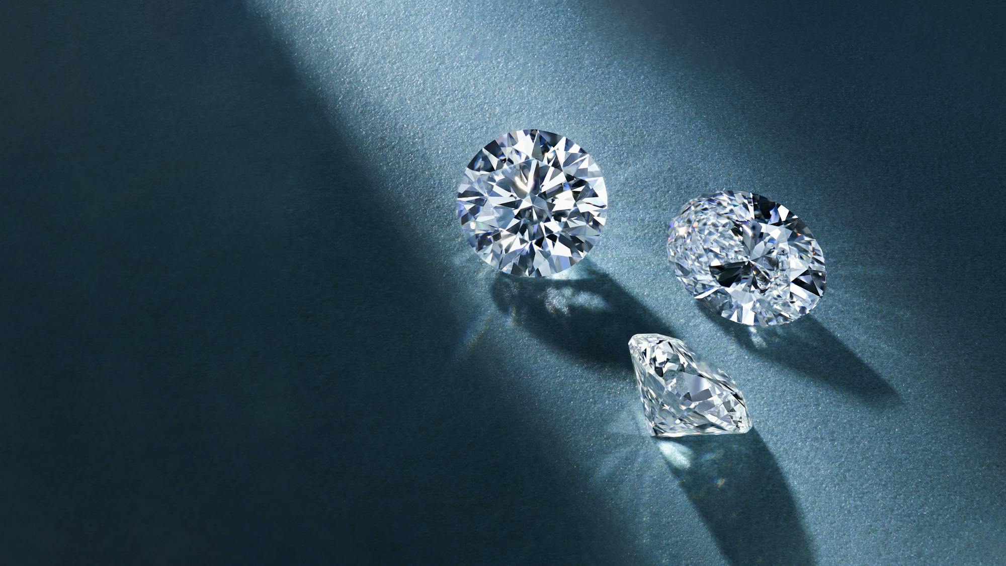 Round and oval lab grown diamonds on blue background.