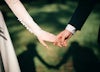 Bride and groom hold hands outside.
