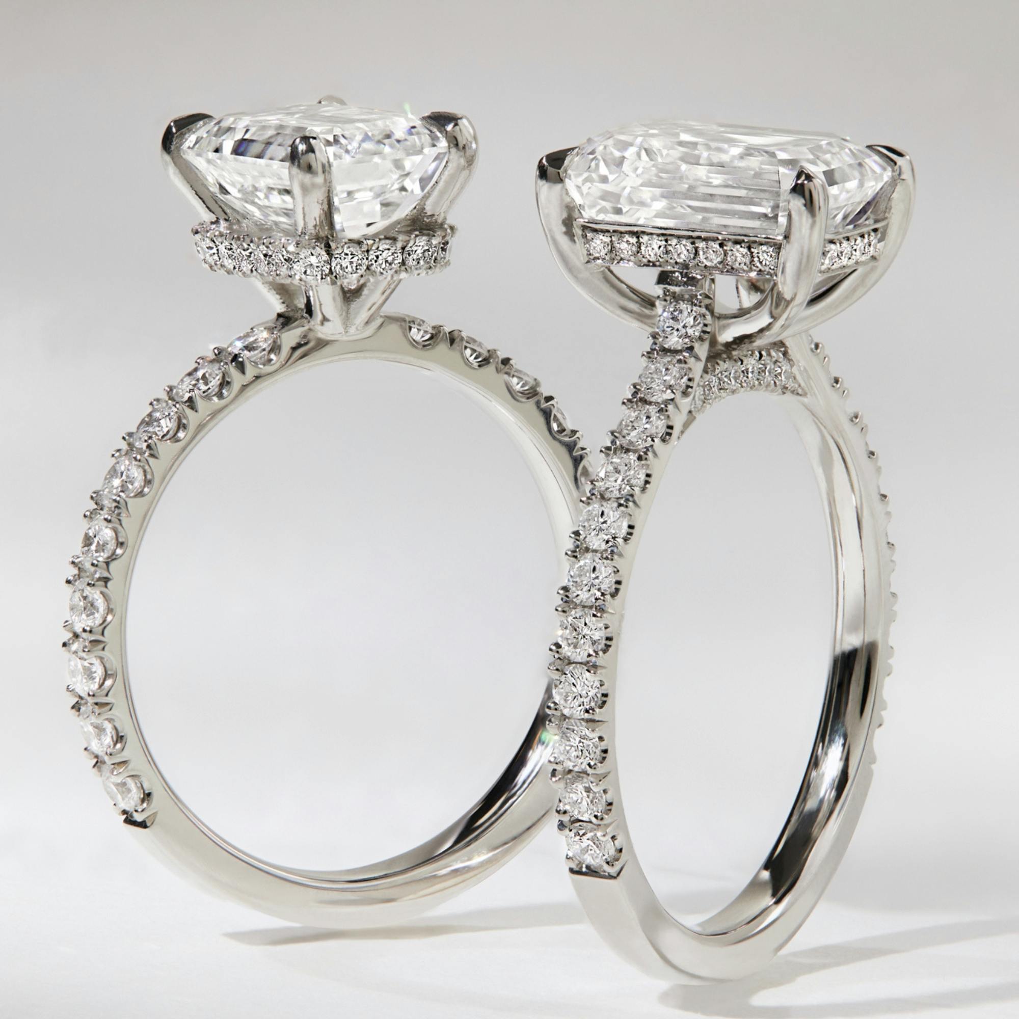 A close-up, side-view of two platinum engagement ring designs.
