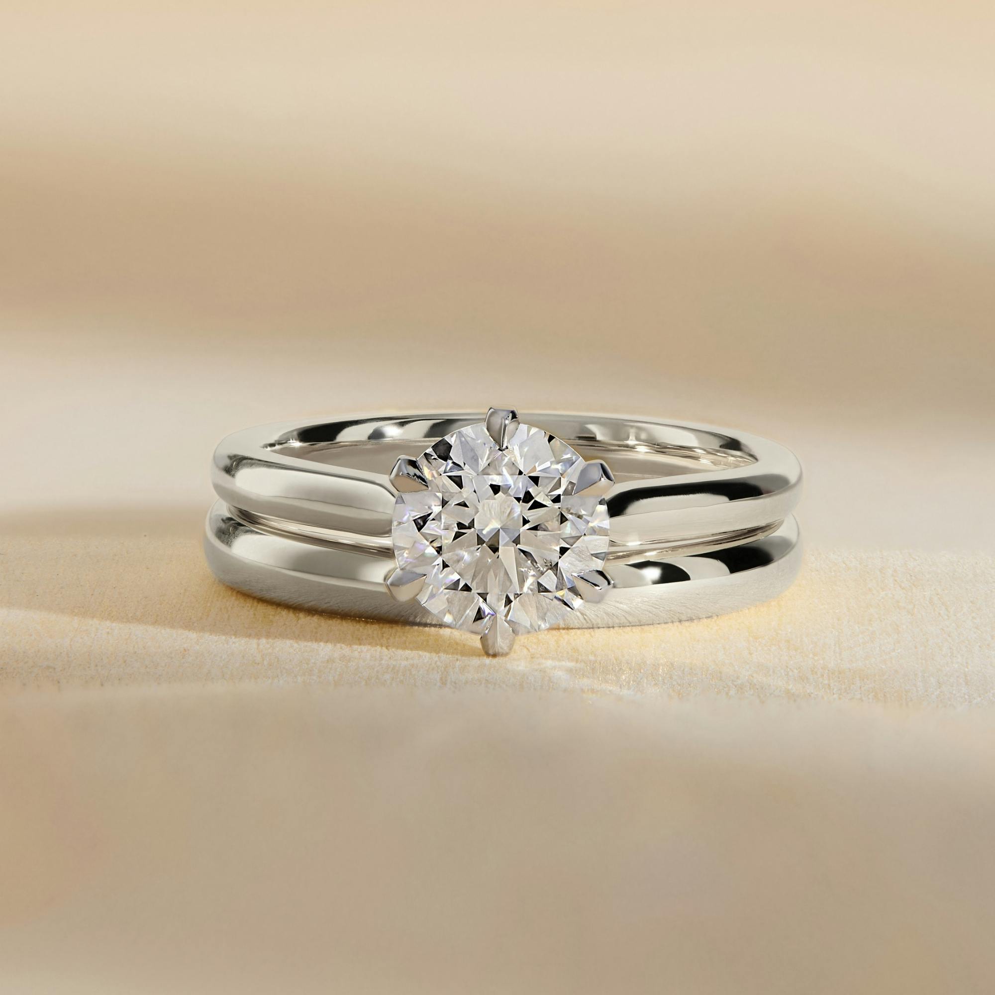 Front-on side-view shot of a diamond solitaire engagement ring in platinum with a six prong setting.