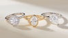 Three engagement rings: one round diamond platinum halo ring, one oval yellow gold rubover ring and one pear diamond ring.