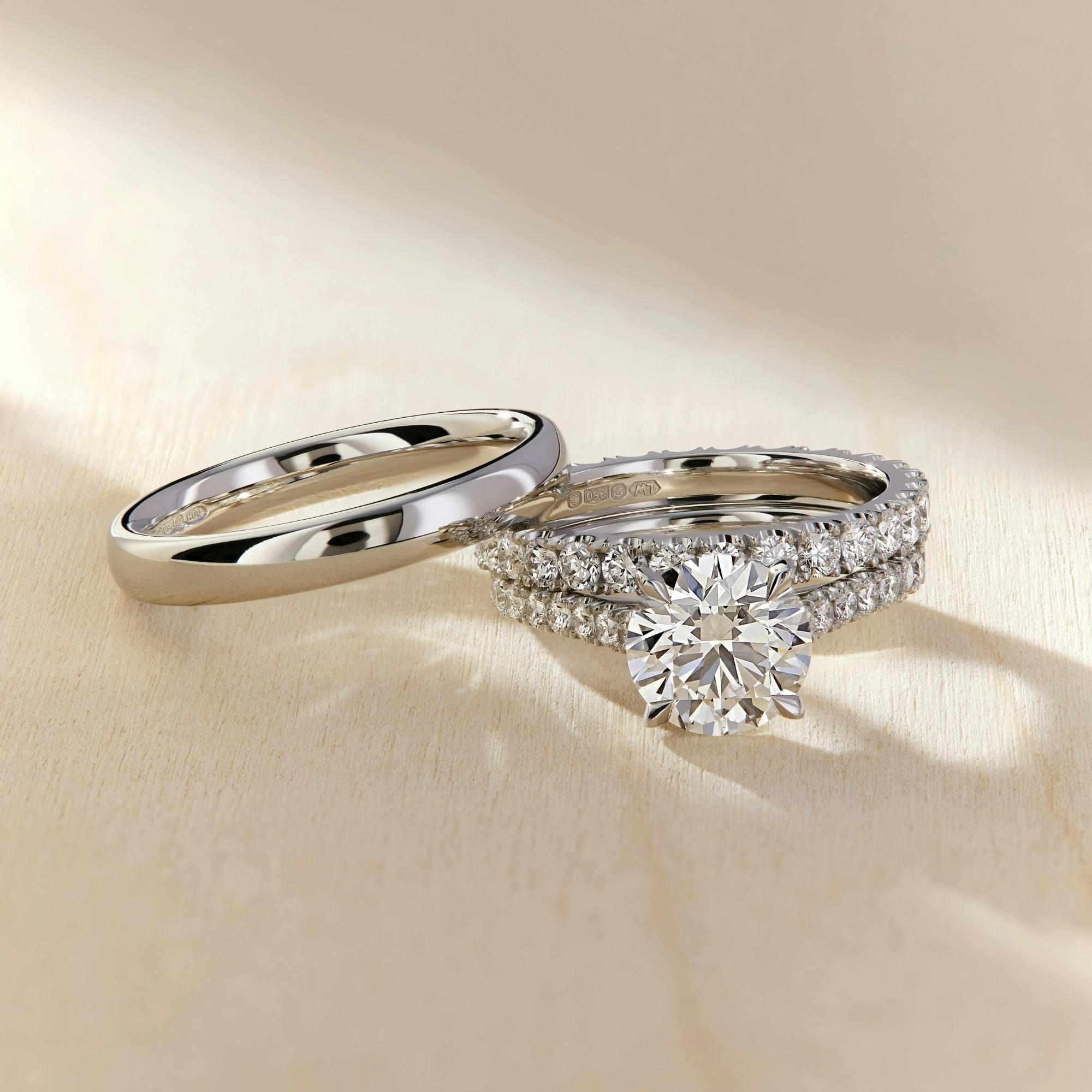 A side-view image of a platinum wedding band resting on a platinum wedfit engagement ring stack.